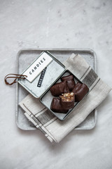 chocolate candy with nuts and dates in gift box on white marble background with copy space