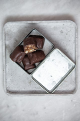 chocolate candy with nuts and dates in gift box on white marble background with copy space