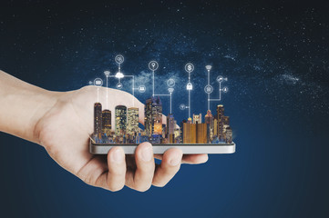 Smart city, building technology and mobile application technology. Hand holding mobile smart phone...