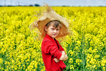 Naklejka na ściany i meble Portrait of a boy in a straw hat on a walk in the field
