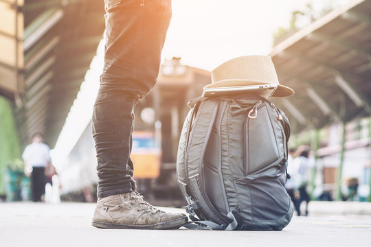 Summer day of Asian man walking and waits train on railway platform. travel bag at the train station with a traveler.sun set, Travel concept. side view.