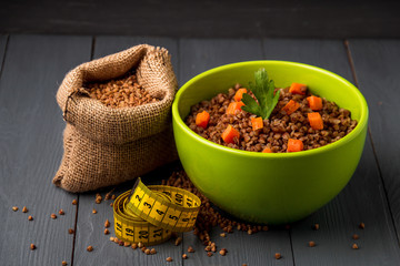 Green bowl of tasty buckwheat porridge on gray wooden table. The concept of a healthy diet.
