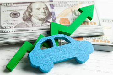 Green arrow graphic up on the background of the car and a stack of money cash dollars. The concept...