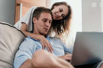 young couple using laptop together when sitting on the couch in spare time