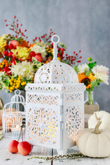 Beautiful white lantern, flowers and pumpkins on the table
