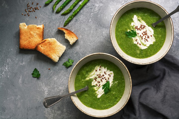Green cream asparagus soup with crispy toasts on a gray background. Overhead view, copy space. - Powered by Adobe