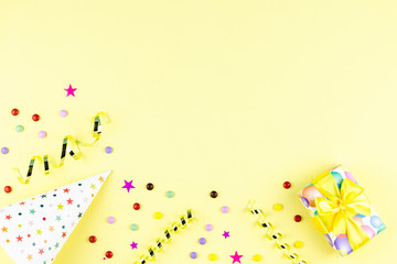 Birthday party background with wrapped gifts, confetti, party hats, decorations, top view