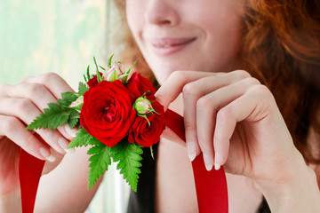 Bridesmaid wearing wrist corsage made of red rose flowers.