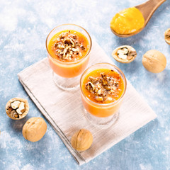 Healthy pumpkin smoothie with walnuts and cinnamon in glasses on rustic background