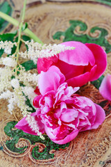 Pink peonies and white astilbe flowers on wooden table.