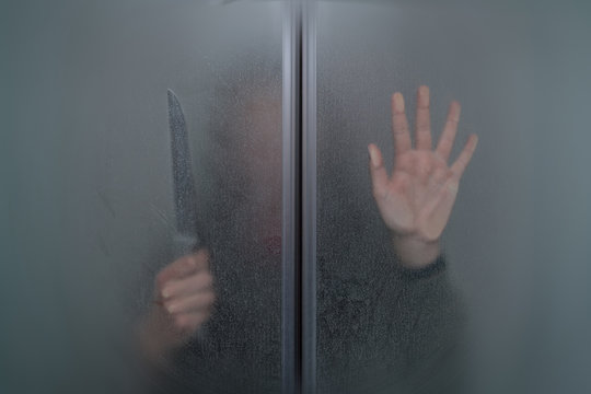 girl with a knife in his hand behind the glass door of the shower in the bathroom