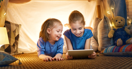 children are playing with tablet in tent