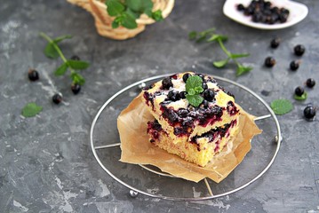 Sweet sliced cake with cornmeal and black currant. Decorated with fresh mint, powdered sugar and berries of frozen black currant.