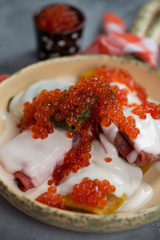 Close-up of crepes with yogurt and red caviar, vertical shot, selective focus