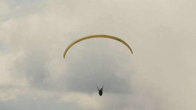 The paraglider flies in the clouds over the mountains on a cloudy day. Extreme sport. Lifestyle. Adrenaline.