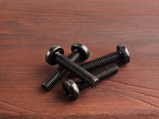 Four screws on a brown background with copy space. Industrial theme