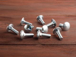 Group of silver color steel screws on brown background. Industrial theme