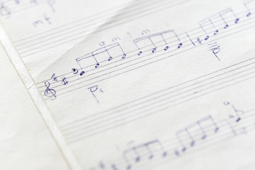 Fragment of an old musical notebook with hand written notes close up