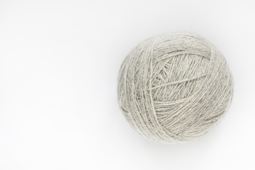 A ball of yarn of natural color on a light background. Close-up. Copy space