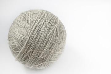 A ball of yarn of natural color on a light background. Close-up. Copy space
