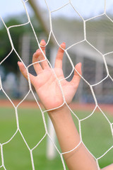 Hand hold on net of soccer goal.