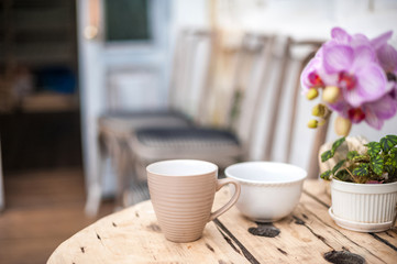 Breakfast, cups on the table in the garden. Textural old vintage table in rustic style and orchid. Potted flowers in a greenhouse close-up and copy space