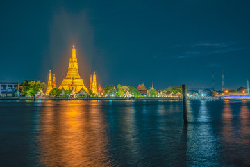 large illuminated temple Wat Arun ratchawararam at twilight the biggest and tallest pagoda in the world beside .Chaophraya river Bangkok Thailand