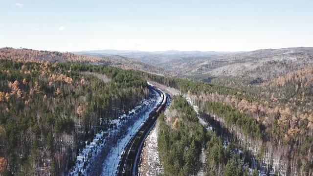 Winter day Aerial drone follow Trans-Siberian railway passengers tourist train near Baikal lake. Cinematic professional footage. High altitude