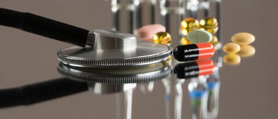 medical stethoscope with pills and ampoules on a mirror background with reflection