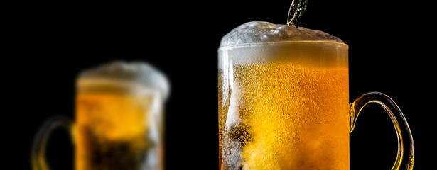 Two large glasses of beer with foam close-up, facing each other, isolated against a black background. Two overflowing glasses of beer with flowing foam. - 267341796