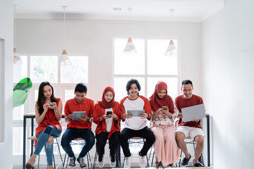 group of young people sitting together using their own gadget in the cafe