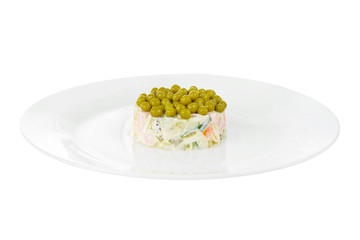 Russian salad with peas, eggs, cucumbers, carrots, ham, sausage, potatoes on plate, side view white isolated background