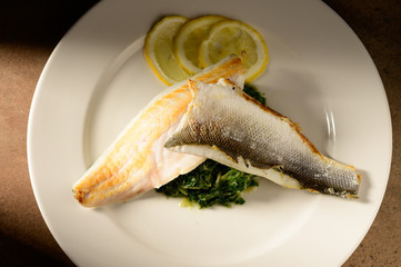 Roasted fish filet decorated with lemon slices on a plate
