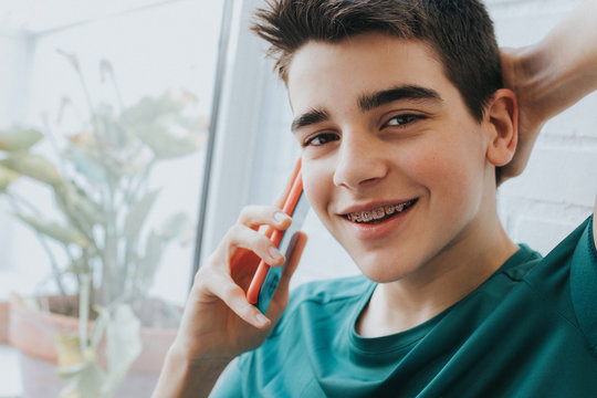 portrait of a male teenager with braces and mobile phone