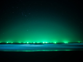 Green light at horizon line over the sea, light from fishing boat.