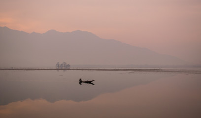 Man rowing his boat on a Peaceful Sunrise