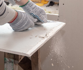 Worker cuts with a knife drywall repair