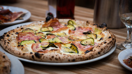 Zucchini capicolo pizza on wooden table, Italian cuisine in Vancouver, Canada