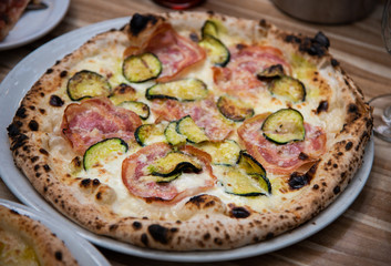 Zucchini capicolo pizza on wooden table, Italian cuisine in Vancouver, Canada