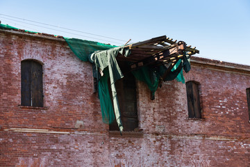 facade of an old brick abandoned building with a destroyed structure