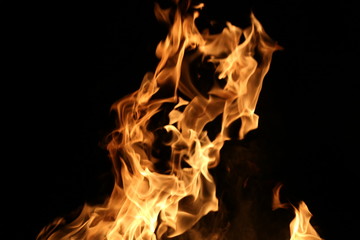 Closeup of a large fire. Wooden planks to the fire. The fire is lit in the night.