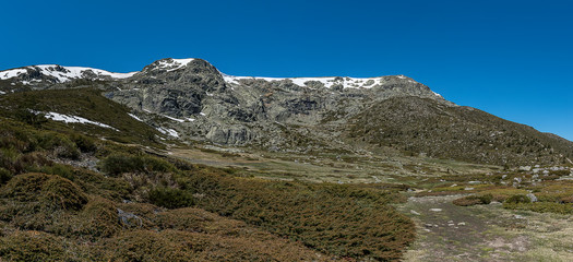 Panoramic landscape of high mountain in spring, with small snowfields. Natural Park of the Sierra de Guadarrama, Madrid, Spain