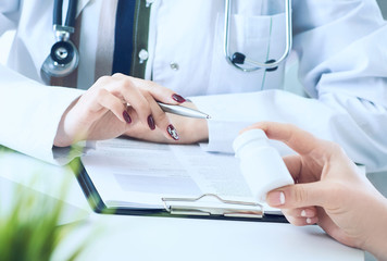 Female doctor hands gives jar of pills to patient hand closeup.