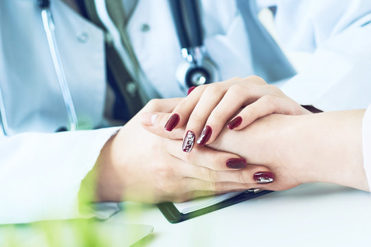 Cropped image of female therapist holding patient's hands during the consultation. Medical ethics and trust concept