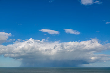 Obraz premium Rain clouds over the ocean with a blue sky above them