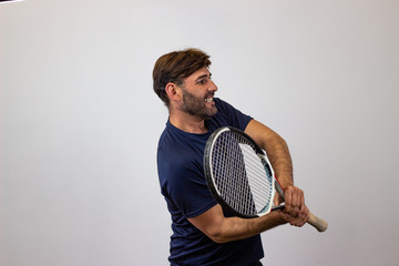 Portrait of handsome young man playing tennis holding a racket with brown hair looking euphoric,...