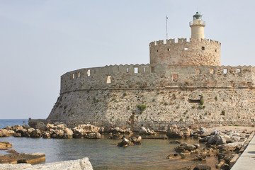 In Mandrake Harbor on the Fort of St Nicholas stands a lighthouse on a stone pier - Lighthouse of St Nicholas Fortress