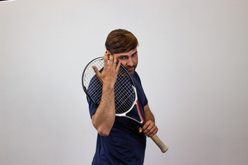 Portrait of handsome young man playing tennis holding a racket with brown hair looking affectionate, their back facing the camera and looking at the camera. Isolated on white background.