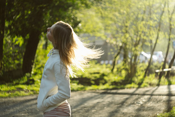 Beautiful blond girl with long hair posing in white hoodie at the forest