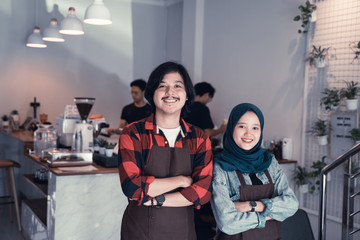 Fototapeta premium young barista and partner smiling to camera. confident couple cafe worker or owner